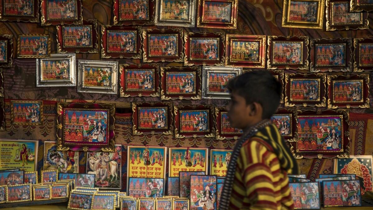 A young Hindu devotee walks past a stall selling religious images during the Gangasagar Mela, at Sagar Island, some 150 kilometres south of Kolkata on January 14, 2020. XAVIER GALIANA / AFP