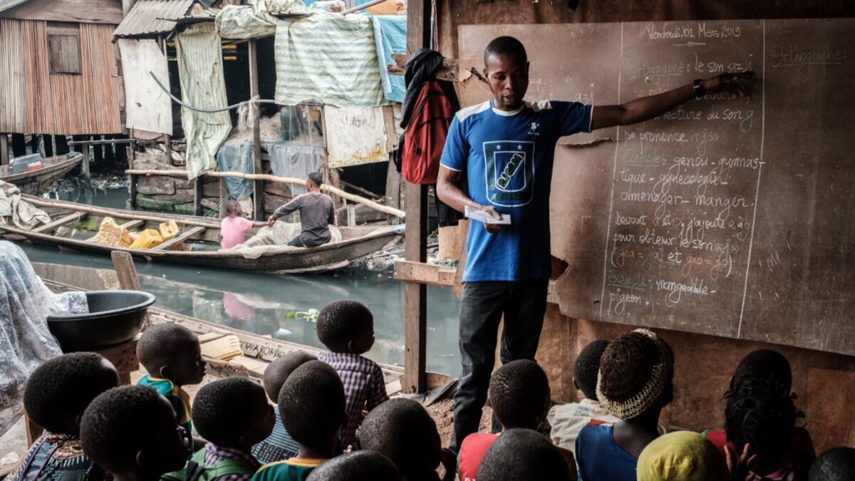 A picture taken on March 1, 2019 shows a teacher speaking to his students during his class at a private school in the Makoko waterfront community in a polluted lagoon in Lagos, Africa’s biggest megalopolis in Nigeria. The sprawling community began in the 19th century as a fishing village for immigrants who settled on the water's edge. As more arrived and land became rare, people started to move out onto the water. Over time, Makoko became a floating realm of perhaps a quarter of a million people, although t