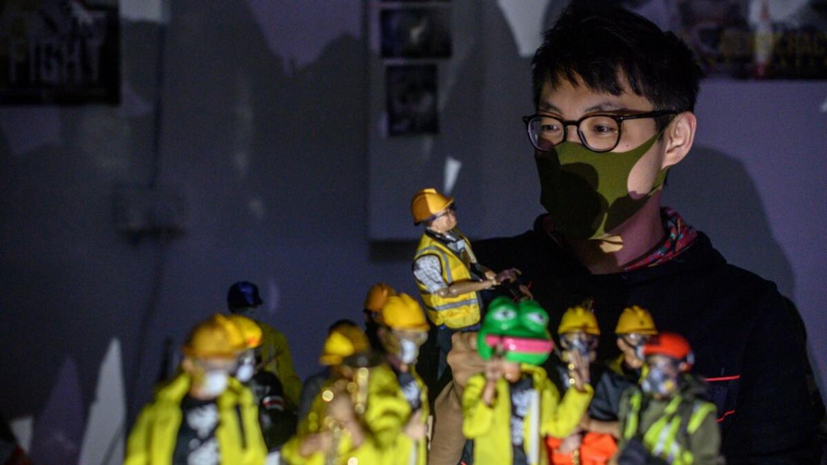 This picture taken on January 14, 2020 shows figurine enthusiast Charlie, who asked to use a pseudonym, posing with 1:6 scale action figures depicting characters involved in the Hong Kong protests, following an interview with AFP in Hong Kong. Intricately detailed Hong Kong protester figurines have become the latest must-have collectables as toy stores recreate the pro-democracy movement's street battles with police in their shop displays.  Philip FONG / AFP