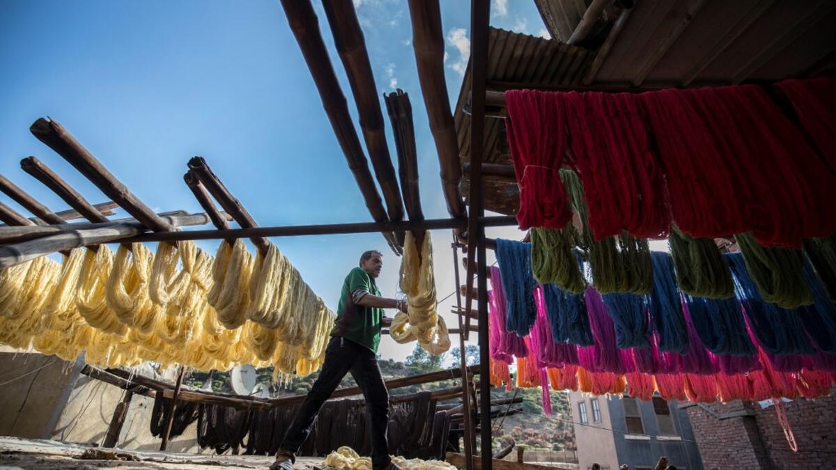 Mohamed Kamal, a 59-year-old dye worker, hangs dyed yarns out to dry in the sun at a traditional hand-dying workshop in the Egyptian capital Cairo's centuries old district of Darb al-Ahmar on January 21, 2020. Khaled DESOUKI / AFP