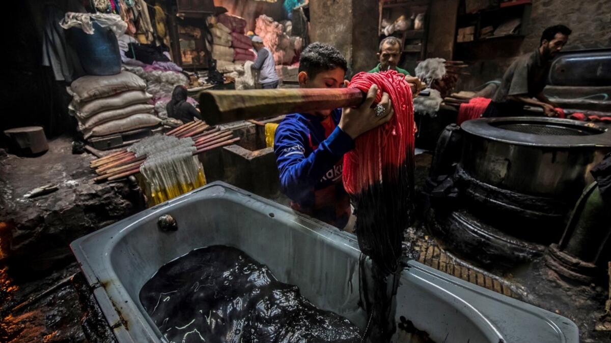 Workers dye yarns at a traditional hand-dying workshop in the Egyptian capital Cairo's centuries old district of Darb al-Ahmar on January 21, 2020. In Cairo's centuries-old Darb al-Ahmar district, Salama Mahmoud Salama's dye workshop is a multi-coloured den of textiles and busy workers colouring all kinds of fabrics. Khaled DESOUKI / AFP