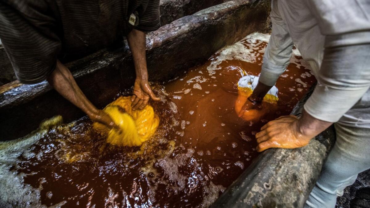 Workers dye yarns in a vat at a traditional hand-dying workshop in the Egyptian capital Cairo's centuries old district of Darb al-Ahmar on January 21, 2020. In Cairo's centuries-old Darb al-Ahmar district, Salama Mahmoud Salama's dye workshop is a multi-coloured den of textiles and busy workers colouring all kinds of fabrics. Khaled DESOUKI / AFP