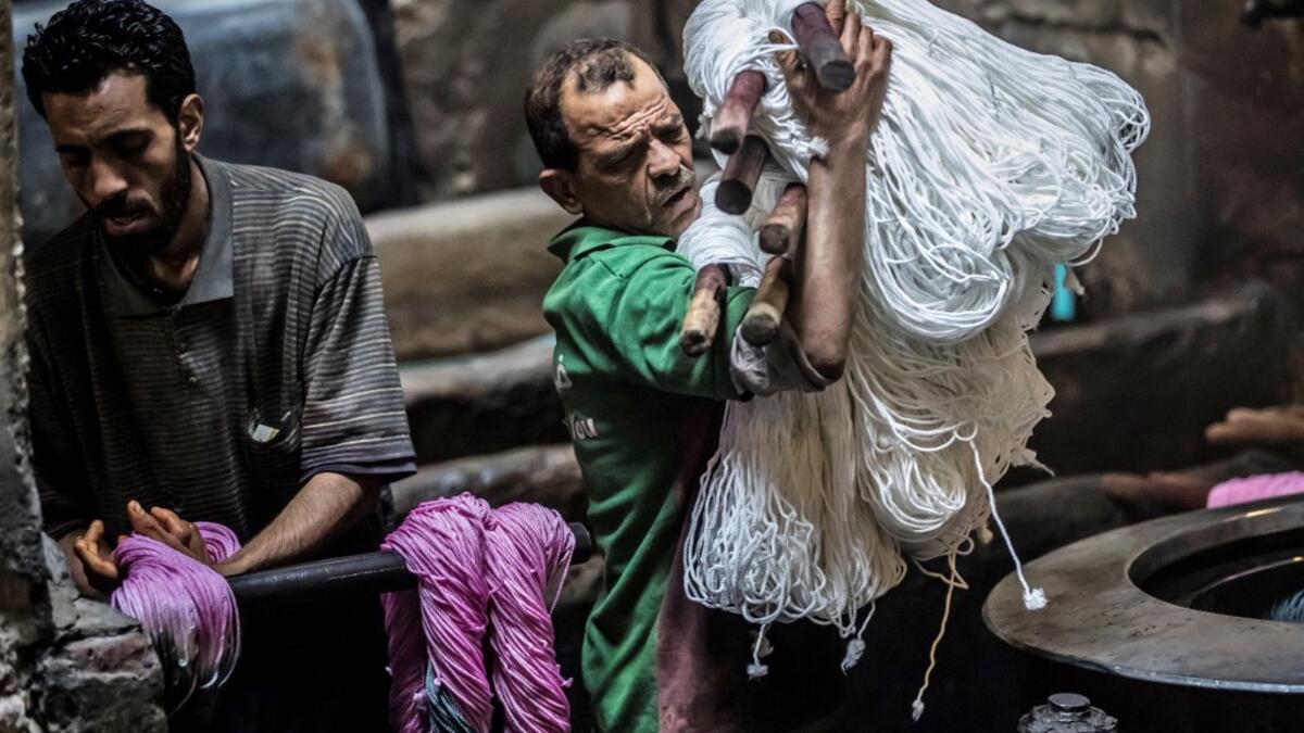 A worker carries undyed yarns to be processed at a traditional hand-dying workshop in the Egyptian capital Cairo's centuries old district of Darb al-Ahmar on January 21, 2020. Khaled DESOUKI / AFP