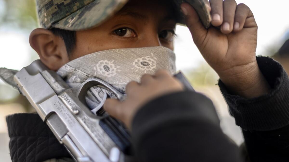 A boy looks on as he holds a gun as the Regional Coordinator of Community Authorities (CRAC-PF) community police force teaches a group of children how to use weapons, at a basketball court in the village of Ayahualtempan, Guerrero State, Mexico, on January 24, 2020. The CRAC-PF vigilante group trains children as young as five so they can protect themselves from drug-related criminal groups operating in the area. AFP