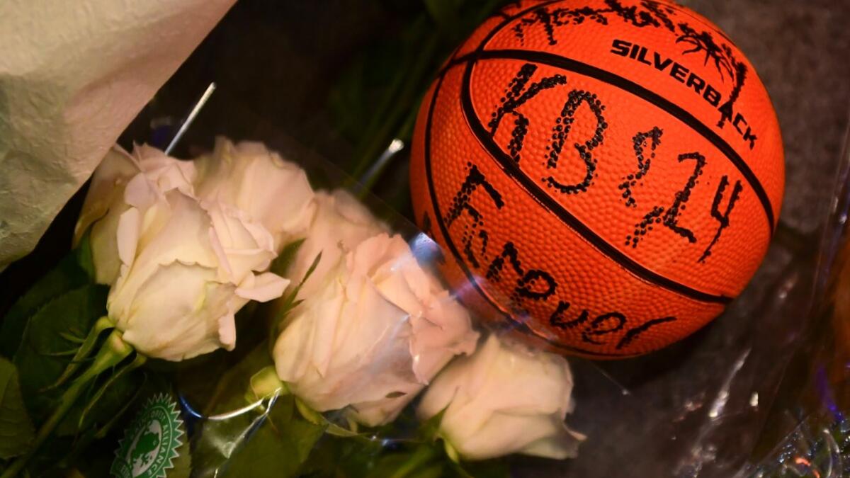 A basketball with the words "KB & 24 Forever" written on it and white roses are placed at a makeshift memorial as fans gather to the mourn the death of NBA legend Kobe Bryant, who was killed along with his daughter and seven others in a helicopter crash on January 26, at LA Live plaza in front of Staples Center in Los Angeles on January 27, 2020. Federal investigators sifted through the wreckage of the helicopter crash that killed basketball legend Kobe Bryant and eight other people, hoping to find clues to