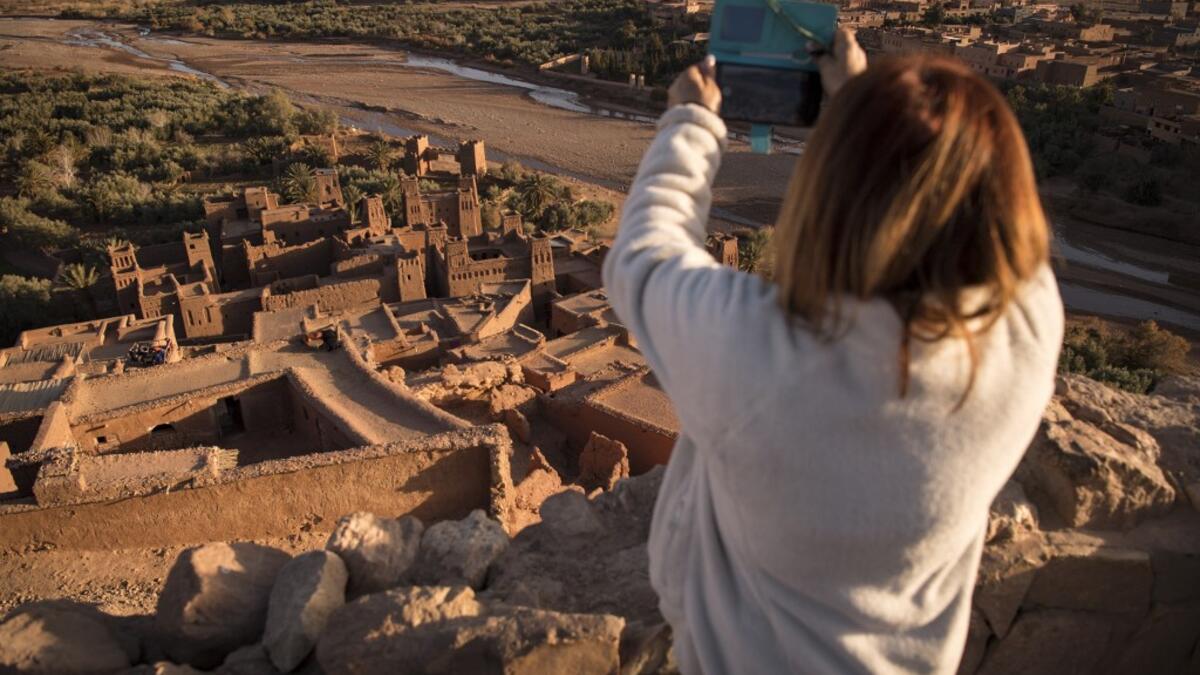 A tourist uses her phone to photograph the Kasbah (ancient fortress) of Ait-Ben-Haddou, where scenes depicting the fictional city of Yunkai from the hit HBO television series "Game of Thrones" were filmed, about 32 kilometres northwest of the city of Ouarzazate south of Morocco's High Atlas mountains on January 27, 2020.  FADEL SENNA / AFP