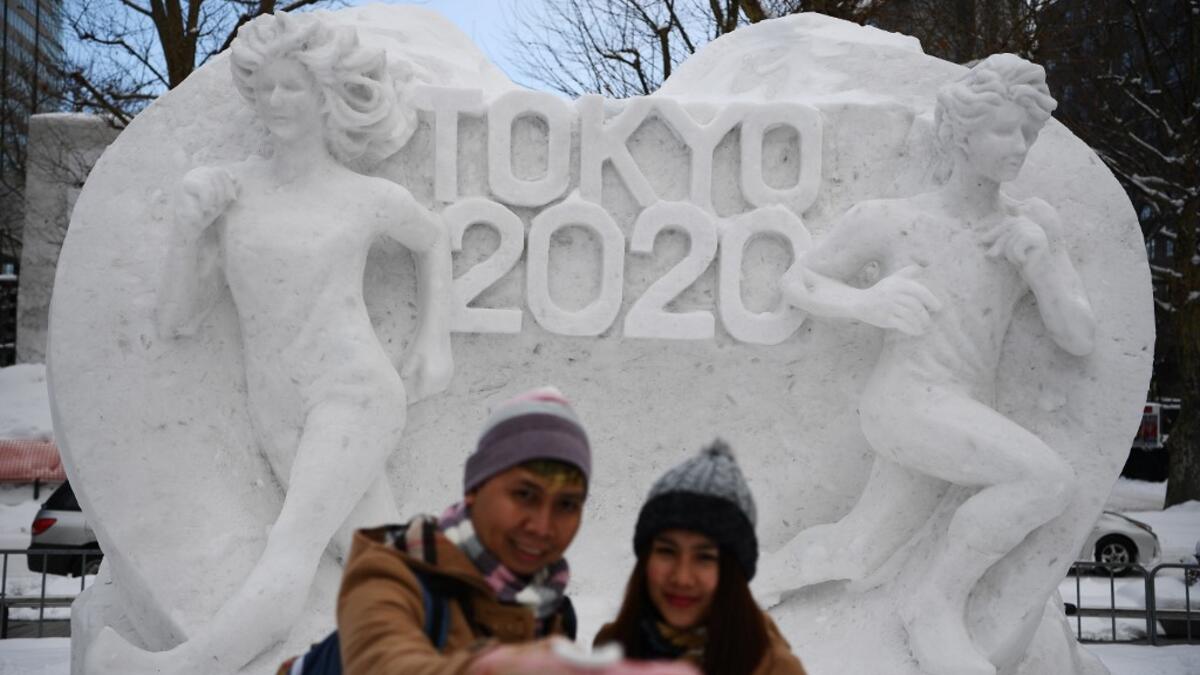 A couple poses for a selfie in front of a snow sculpture with a motif of the upcoming Tokyo 2020 Olympic Games, during the Sapporo Snow Festival in Sapporo on February 4, 2020. The snow festival, which opened January 31 in the capital of Hokkaido in northern Japan. CHARLY TRIBALLEAU / AFP
