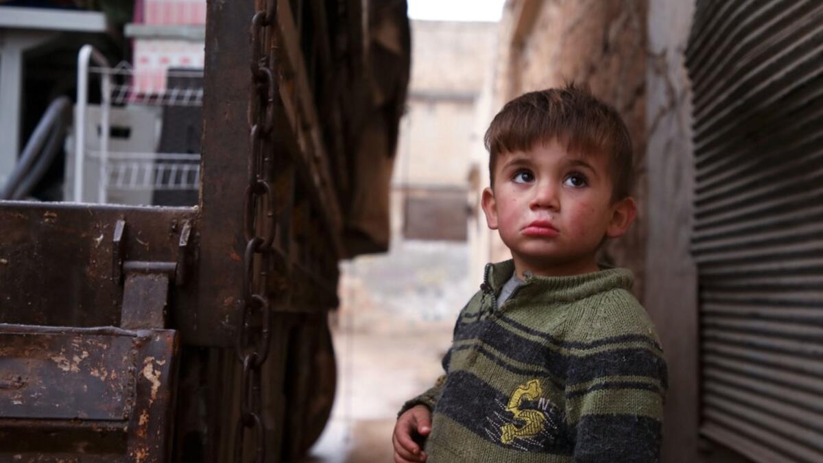 A Syrian child looks up as relatives load belongings onto a truck ahead of leaving the town of Binnish in the northwestern province of Idlib, on February 4, 2020, amid an ongoing offensive by pro-regime forces. A Russian-backed Syrian government offensive against the country's last rebel enclave of Idlib has displaced more than half a million people in two months, according to the United Nations. The wave of displacement, which coincides with a biting winter, is one of the largest since the start of the Syr