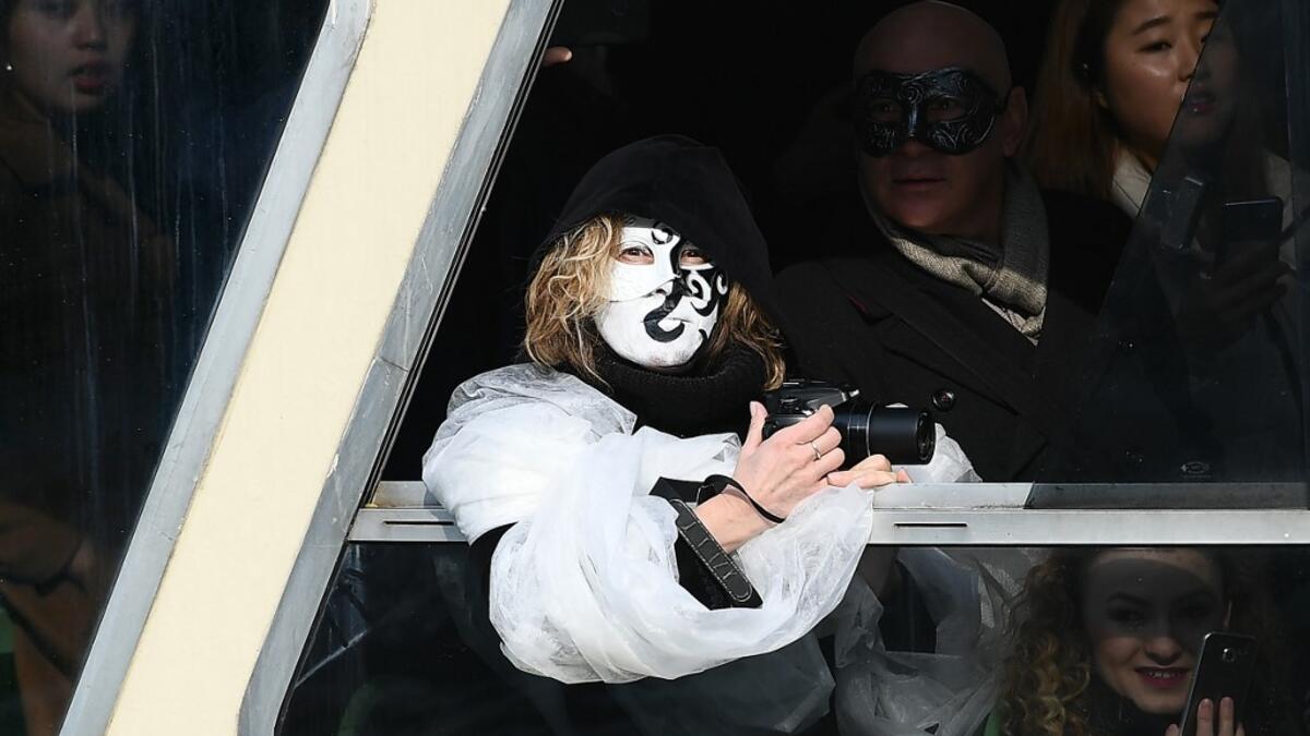 A masked reveller looks on aboard a ferry on the Grand Canal during the traditional regatta which officially opens the Carnival in Venice, on February 09, 2020. The Venice's carnival takes place until February 25, 2020. Vincenzo PINTO / AFP