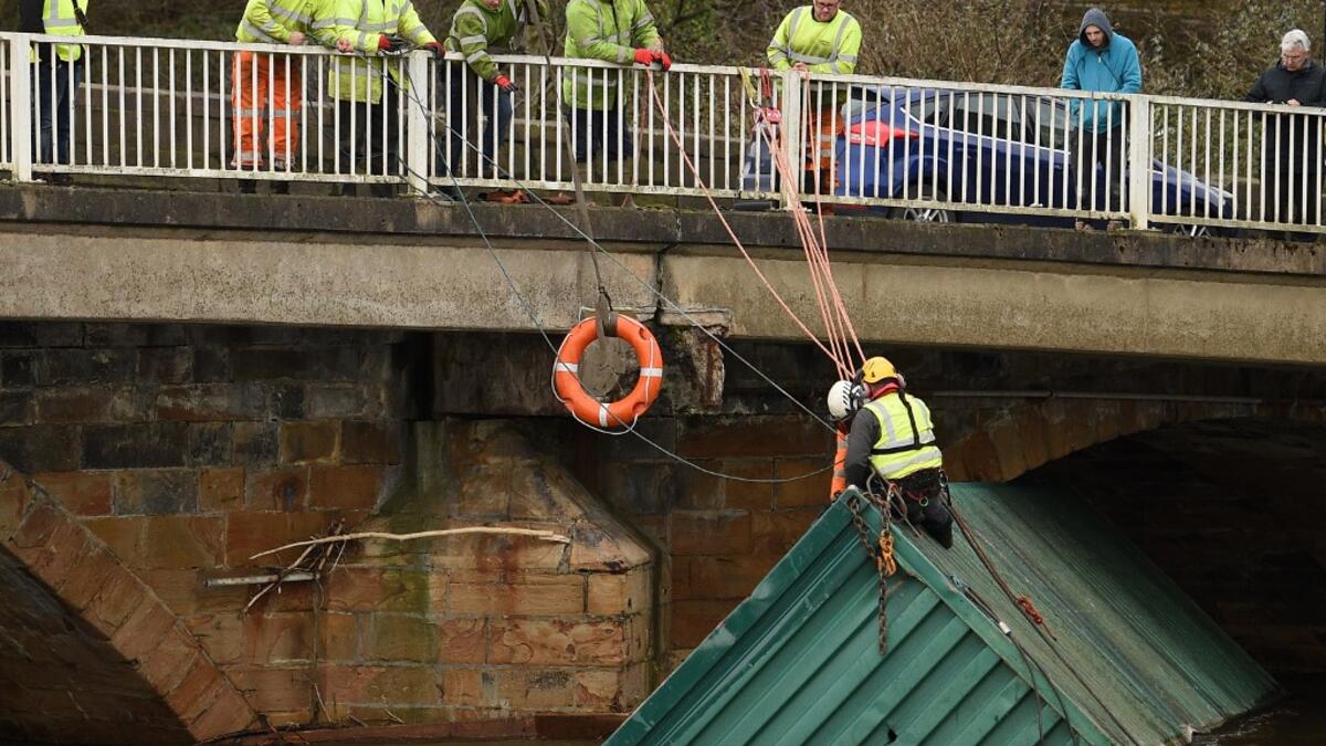 Workers secure a shipping container, lodged under the Rastrick Bridge, after it floated down the River Calder in Brighouse, northern England, on February 10, 2020 after the flooding brought on by Storm Ciara. Storm Ciara grounded hundreds of flights Monday and left swatches of Europe without power after unleashing torrential rain and causing flash flooding that cancelled football matches in Britain. Oli SCARFF / AFP