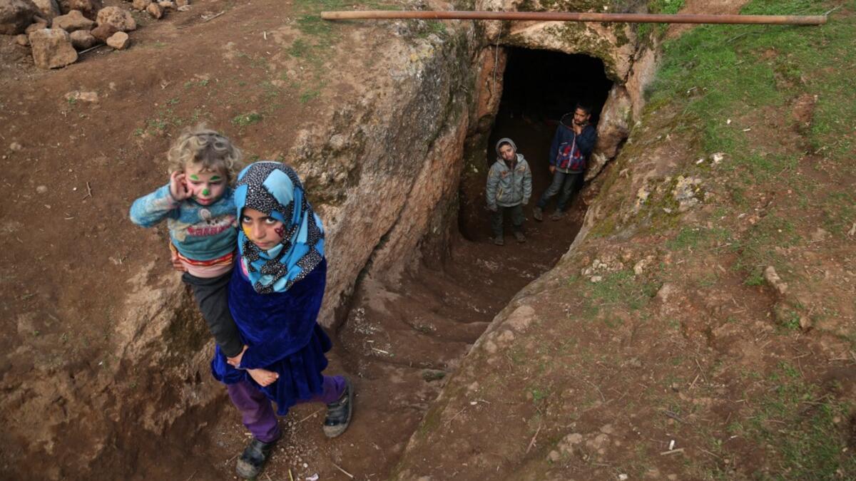 Children walk through the entrance of an underground shelter where several families of internally displaced Syrians from Aleppo and Idlib provinces are taking refuge, in the village of Taltunah about 15 kilometres northwest of Idlib in the northwestern Idlib province, on February 23, 2020. Aref TAMMAWI / AFP