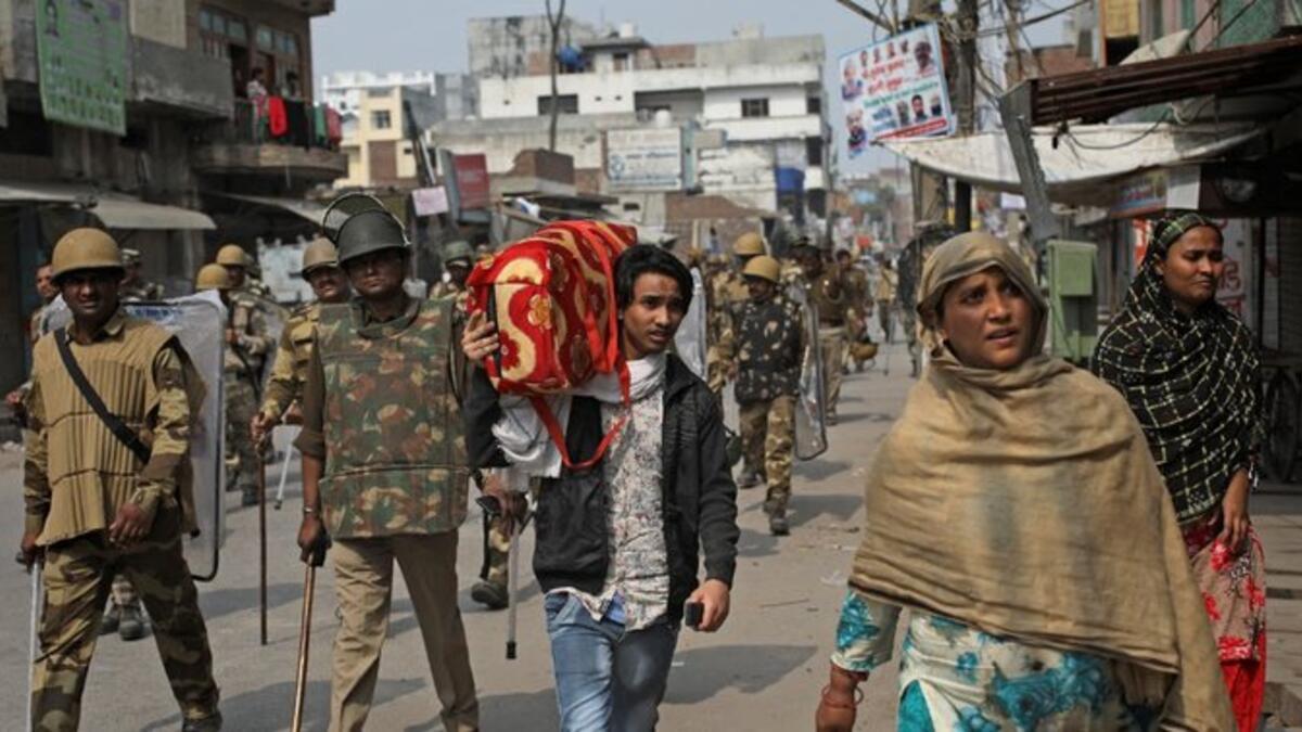 An Indian Muslim family leaves the area as Indian paramilitary soldiers patrol a street vandalized in Tuesday's violence in New Delhi, India, Thursday, Feb. 27, 2020. (AP Photo)