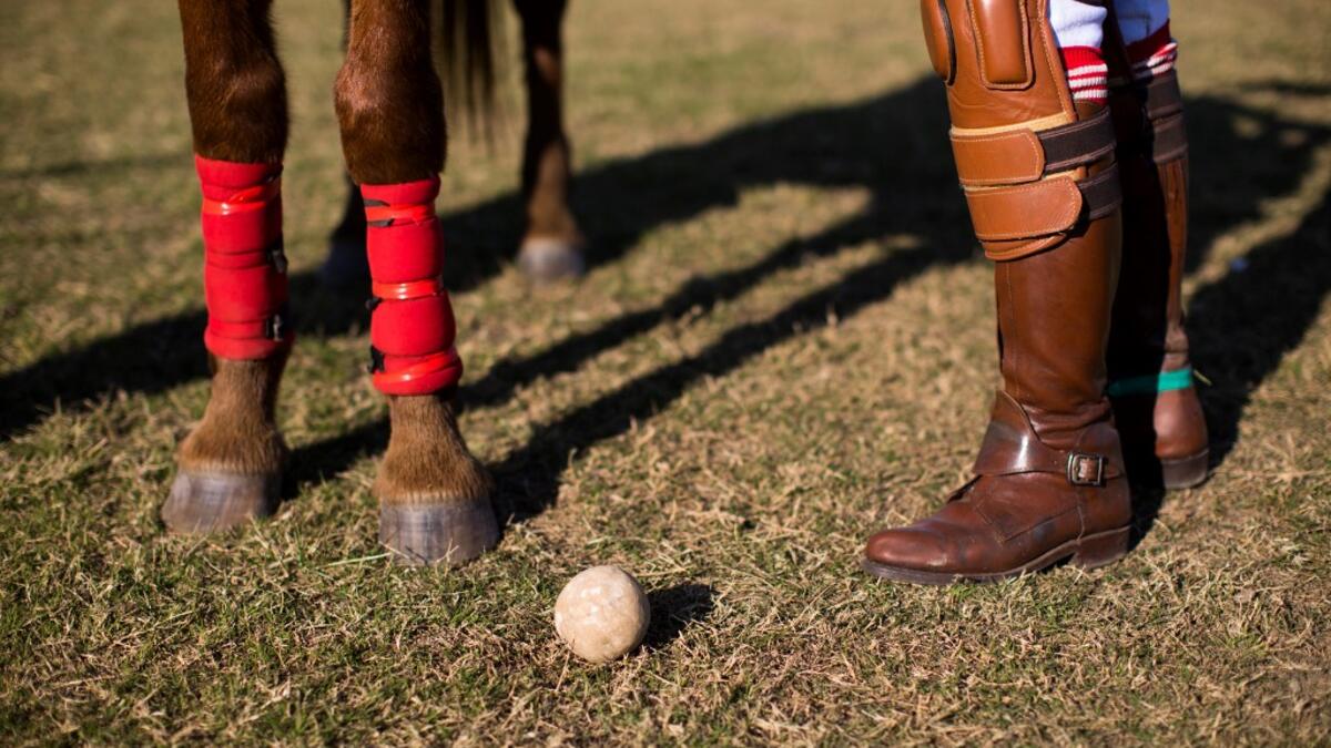 In this photograph taken on January 11, 2020, Linthoingambi Kangjei Lup Polo Club player Shanglenmayum Sangeeta stands next to her Manipuri pony as she adjusts the length of the stirrups leather before the start of their 15th Women's State Polo Tournament match at the Mapal Kangjeibung (Polo Ground) in Imphal, the capital of the northeastern Indian state of Manipur. Laishram Thadoi's face is a picture of concentration as she adjusts her helmet and prepares to play in Manipur, the remote Indian state regarde