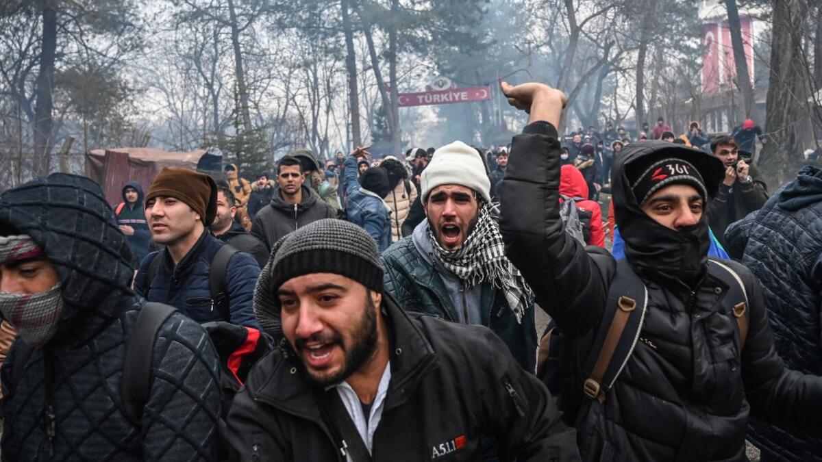 Migrants react as Greek anti-riot police officers use tears gas on the buffer zone Turkey-Greece border, at Pazarkule, in Edirne district, on February 29, 2020. Thousands of migrants stuck on the Turkey-Greece border clashed with Greek police on February 29, 2020. Ozan KOSE / AFP