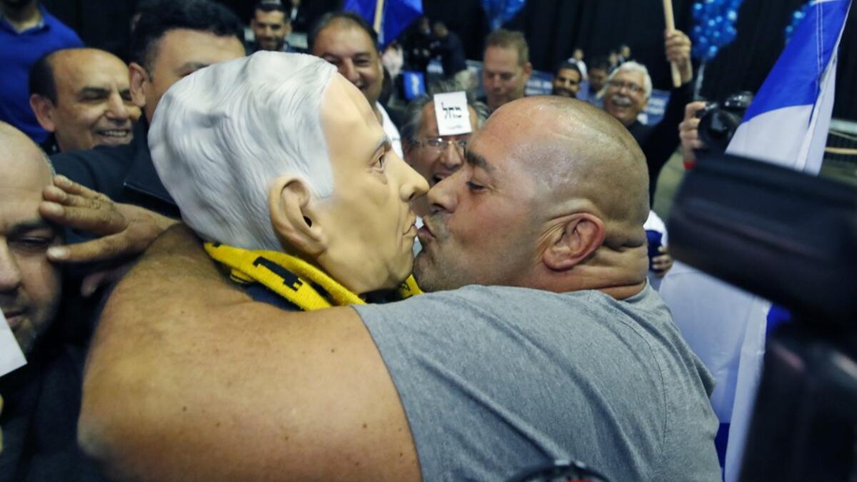 A man kisses another wearing a "Benjamin Netanyahu" face mask as they celebrate at the Likud party's electoral headquarters in the coastal city of Tel Aviv on March 2, 2020, after polls officially closed. Netanyahu appeared to lead his main challenger following elections with multiple exit polls putting his right-wing Likud several seats ahead of the centrist Blue and White party. Exit polls by three Israeli television networks, released after polls closed, gave Likud between 36 and 37 seats in Israel's 120