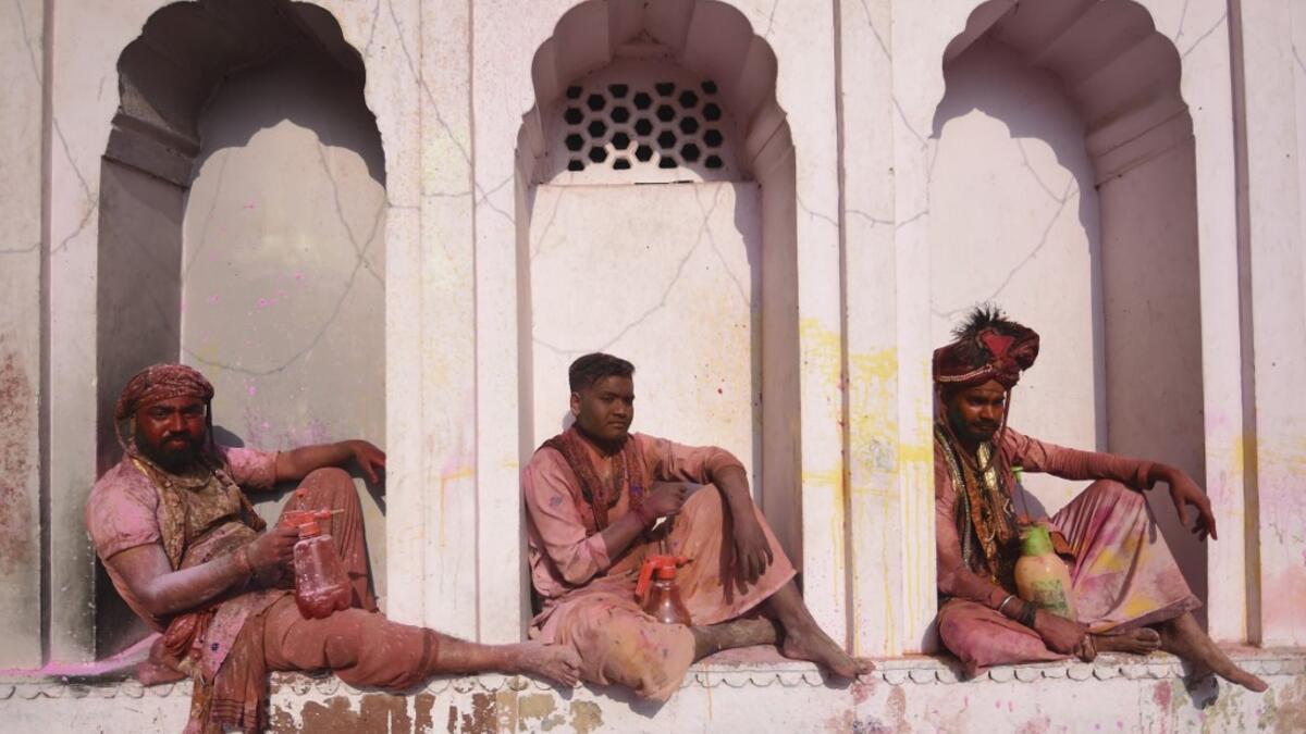 Hindu devotees sit in the columns of a temple as they take a break from participating in Holi celebrations, the spring festival of colours, during a traditional gathering at a temple in Nandgaon village in Uttar Pradesh state on March 5, 2020. Holi is observed in India at the end of the winter season on the last full moon of the lunar month. Money SHARMA / AFP