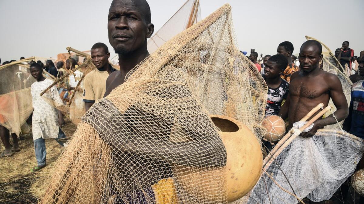 A fisherman poses with a fishing net and a calabash before attending the Argungu fishing and cultural festival at Argungu Town, Kebbi State, in northwest Nigeria, on March 14, 2020. Argungu fishing and cultural festival is one of the oldest and most widely attended festivals in the country dating back many generations, featuring series of water competitions and traditional games. The festival returned after 10 years suspension due to insecurity in northwest Nigeria. PIUS UTOMI EKPEI / AFP
