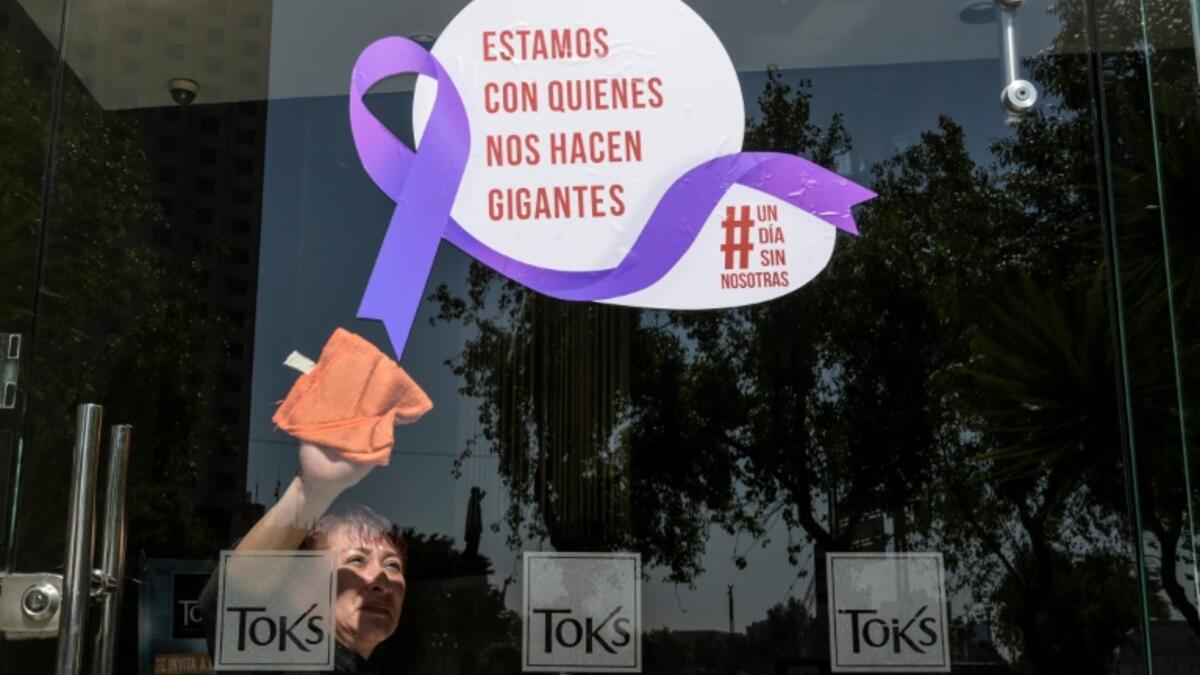 A woman cleans the glass door of a Mexico City restaurant with a sign reading 'We stand with those who make us giants' during Monday's 'A Day Without Us' protest (AFP)