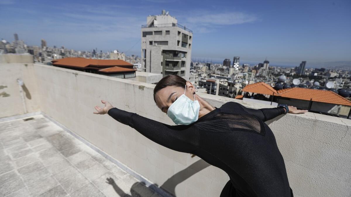 Sherazade Mami, a 28-year-old Tunisian professional dancer and performer at the Caracalla dance theatre and a teacher at the Caracalla dance school, practices while wearing a surgical mask on the roof of her apartment building in the suburb of Dekwaneh on the eastern outskirts of Lebanon's capital Beirut on April 4, 2020. Due to the confinement regulations imposed to combat the COVID-19 coronavirus pandemic, Mami opted to continue practicing on her rooftop to remain in shape. JOSEPH EID / AFP