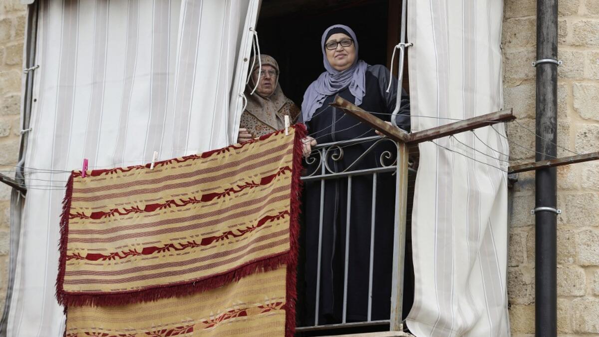 Lebanese women stand at their balcony during confinement at home due to the COVID-19 pandemic, in the historic part of the southern coastal city of Sidon (Saida), on April 6, 2020. Lebanon's President called on international donors to provide financial assistance to the crisis-hit country as it grapples with a severe economic downturn compounded by the novel coronavirus pandemic. JOSEPH EID / AFP