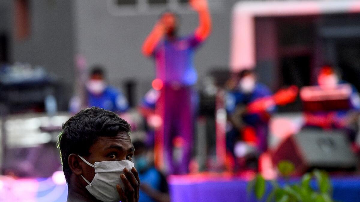A resident wearing a facemask watches a music band formed by Sri Lankan Navy personnel as they play outside a housing complex during a government-imposed nationwide lockdown as a preventive measure against the COVID-19 coronavirus, in Colombo on April 9, 2020. ISHARA S. KODIKARA / AFP