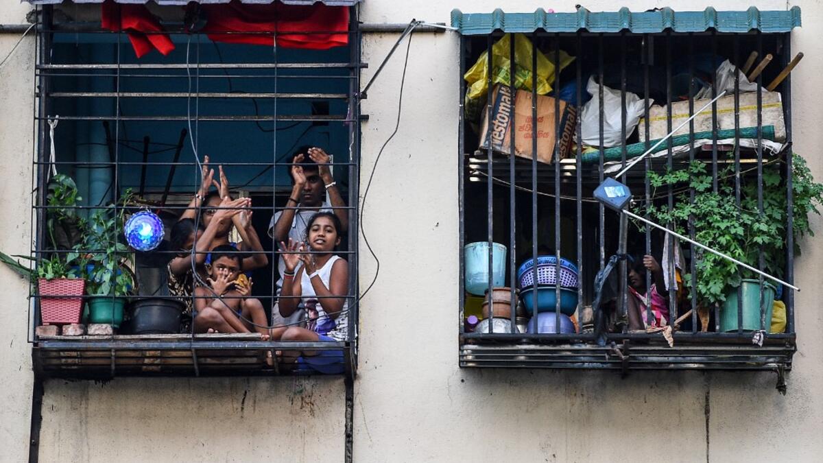 Residents watch from their flats' windows a music band formed by Sri Lankan Navy personnel as they play outside a housing complex during a government-imposed nationwide lockdown as a preventive measure against the COVID-19 coronavirus, in Colombo on April 9, 2020. ISHARA S. KODIKARA / AFP