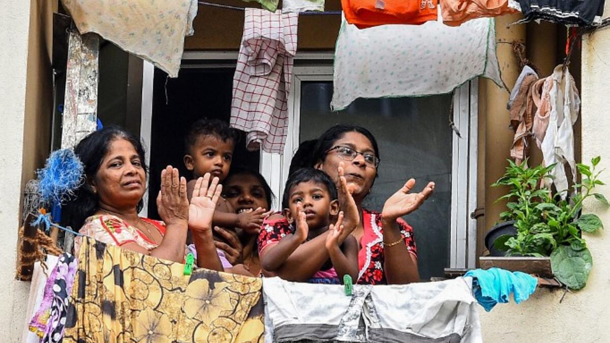 Residents watch from their flat's window a music band formed by Sri Lankan Navy personnel as they play outside a housing complex during a government-imposed nationwide lockdown as a preventive measure against the COVID-19 coronavirus, in Colombo on April 9, 2020. ISHARA S. KODIKARA / AFP