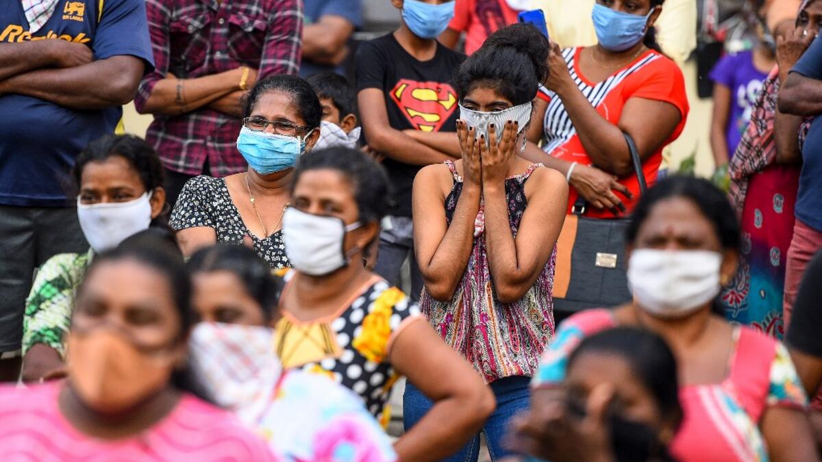 Residents wearing facemasks watch a music band formed by Sri Lankan Navy personnel as they play outside a housing complex during a government-imposed nationwide lockdown as a preventive measure against the COVID-19 coronavirus, in Colombo on April 9, 2020. ISHARA S. KODIKARA / AFP