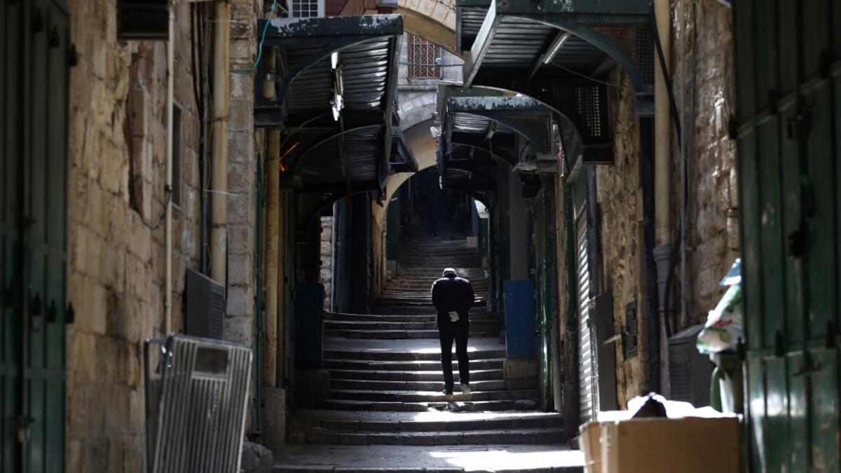 A man wearing disposable gloves amid the COVID-19 pandemic, walks the empty Via Dolorosa, or Way of the Cross, believed to be the route Jesus walked carrying the cross on the way to crucifixion, in Jerusalem's Old City, on April 7, 2020. All cultural sites in the Holy Land are shuttered, regardless of their religious affiliation, as authorities seek to forestall the spread of the deadly respiratory disease, which will prevent Christians from congregating for the Easter service, this coming Sunday for Cathol