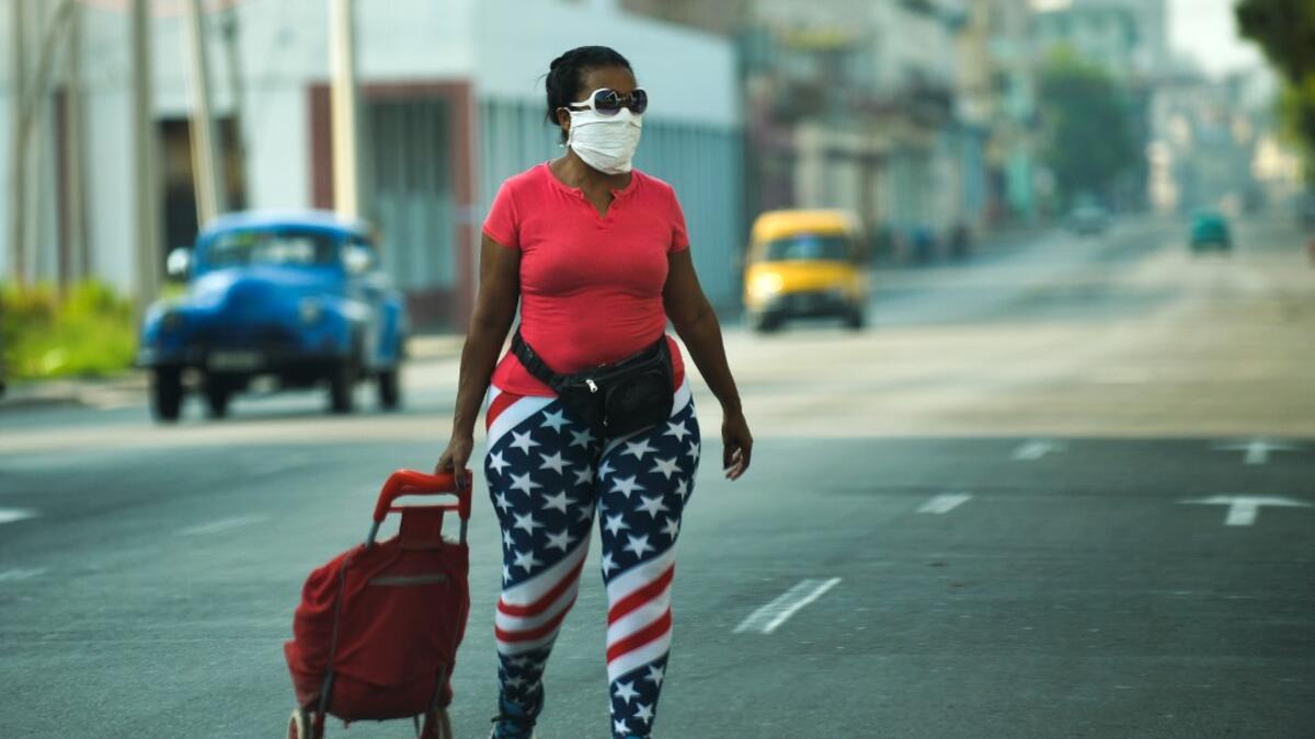 A woman wearing tights depicting the US flag and a face mask, walks along a street in Havana, on April 13, 2020. While Cuba tries to stop the spread of the coronavirus on the island, with 726 cases, voices can be heard to demand the lifting of the US embargo to facilitate the arrival of medical products. YAMIL LAGE / AFP