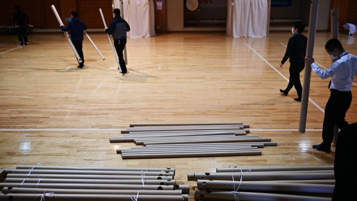 This photo taken on April 14, 2020 shows workers from Voluntary Architects' Network preparing to build a partition with cardboard pillars at a shelter provided by Kanagawa prefecture for people who can’t afford to rent an apartment and used to stay at designated internet cafes, which are closed due to the COVID-19 coronavirus outbreak state of emergency, at a judo sport hall in Yokohama, Kanagawa prefecture. CHARLY TRIBALLEAU / AFP