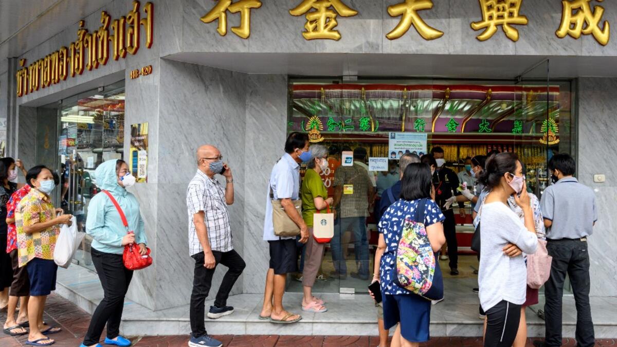 People wearing face masks amid fears of the spread of COVID-19 coronavirus line up to sell their jewelries in front of a gold shop in Bangkok's Chinatown on April 15, 2020. Hundreds of Bangkok residents rushed to goldsmith shops in order to sell their jewelries as gold prices reached its highest levels since 2012. Mladen ANTONOV / AFP