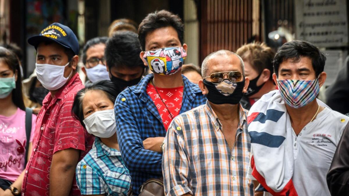 People wearing face masks amid fears of the spread of COVID-19 coronavirus line up to sell their jewelries in front of a gold shop in Bangkok's Chinatown on April 15, 2020. Hundreds of Bangkok residents rushed to goldsmith shops in order to sell their jewelries as gold prices reached its highest levels since 2012. Mladen ANTONOV / AFP