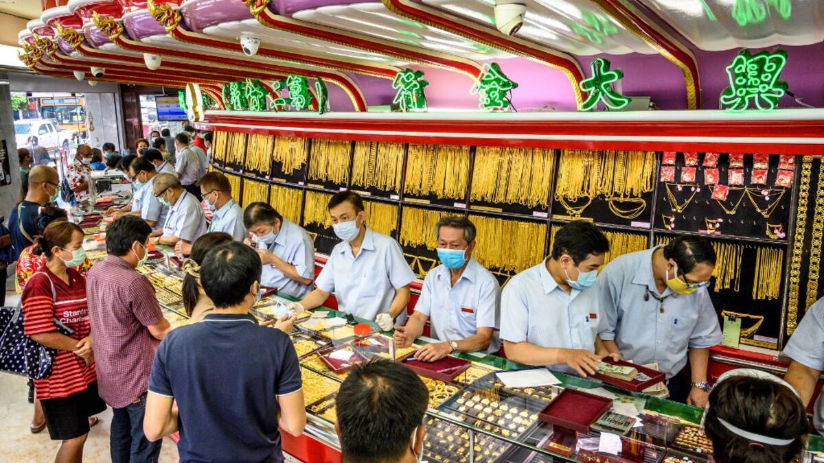 People wearing face masks amid fears of the spread of COVID-19 coronavirus sell their jewelries in a gold shop in Bangkok's Chinatown on April 15, 2020. Hundreds of Bangkok residents rushed to goldsmith shops in order to sell their jewelries as gold prices reached its highest levels since 2012. Mladen ANTONOV / AFP