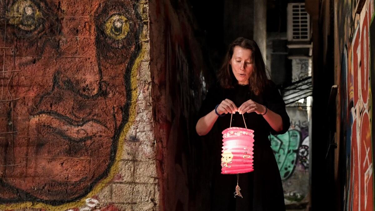 A woman lights a candle with a "Holy Fire" from small candles left on a path outside the Metochion (embassy church) of the Holy Sepulchre in Athens, where the Holy Light was brought earlier today from Jerusalem for the resurrection service on April 18, 2020 as part of the Orthodox Easter celebrations. The strict quarantine measures against the spread of the COVID-19 (the novel coronavirus) keeps churches empty during the Orthodox Easter services and faithfuls are not allow to light their candles with the Ho