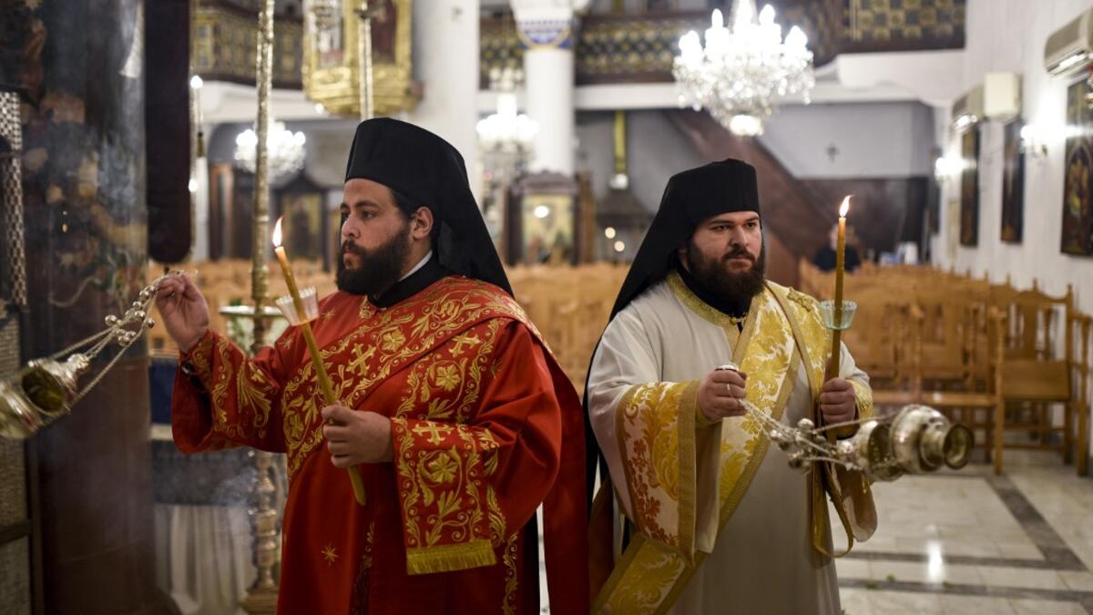 Deacons swing incense censers during the Easter Vigil at the Greek Orthodox Church of Saint Savvas in the old walled city of the Cypriot capital Nicosia on April 18, 2020, as prayers are held without a congregation due to the COVID-19 coronavirus pandemic. Amir Makar / AFP