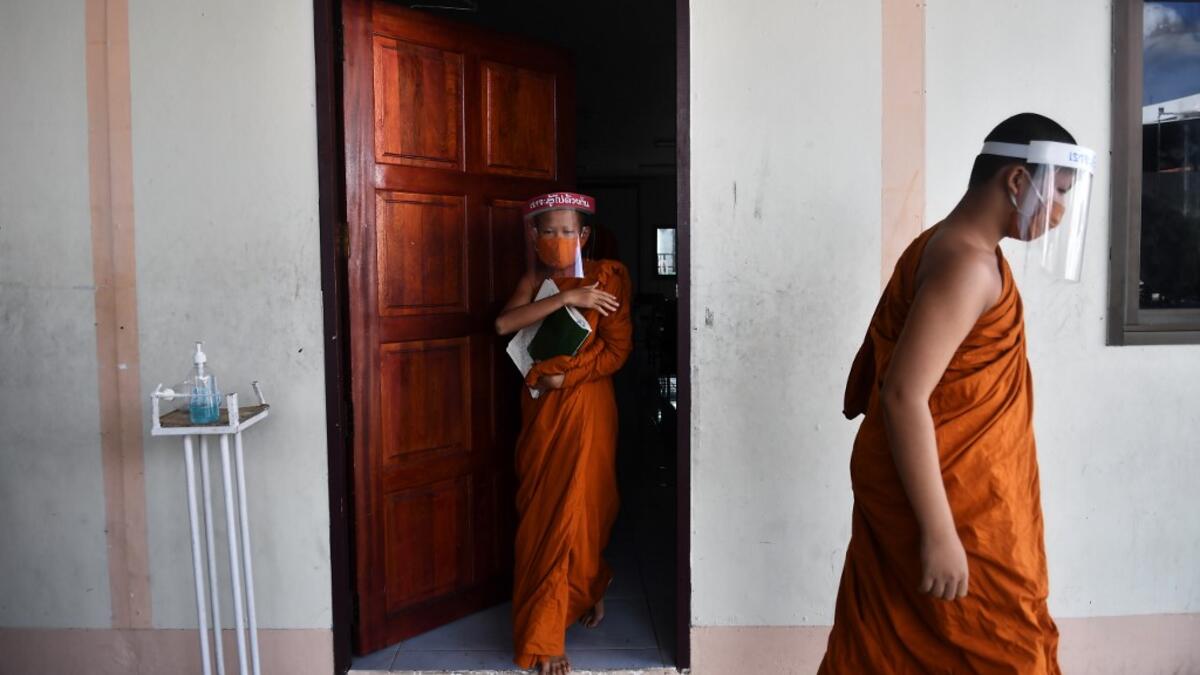 Novice monks wearing face shields as a preventive measure against the spread of the COVID-19 coronavirus leave the classroom after religious studies at Wat Molilokkayaram Buddhist temple in Bangkok on April 20, 2020. Lillian SUWANRUMPHA / AFP