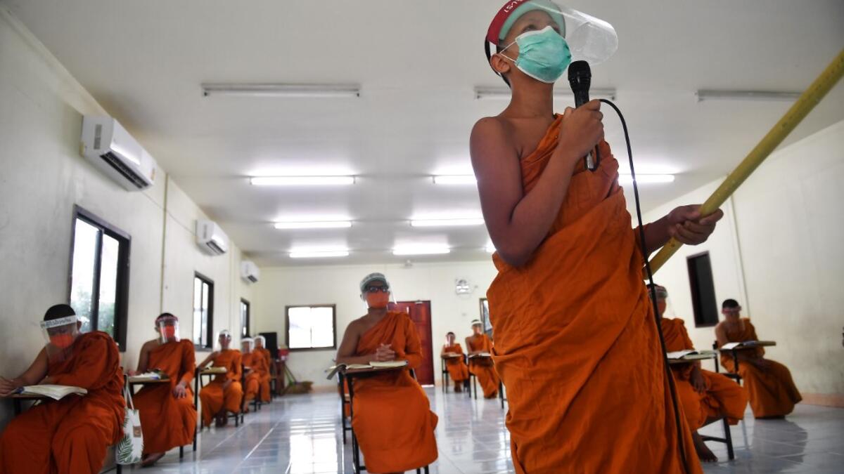 Novice monks wearing face shields as a preventive measure against the spread of the COVID-19 coronavirus attend religious studies at Wat Molilokkayaram Buddhist temple in Bangkok on April 20, 2020. Lillian SUWANRUMPHA / AFP