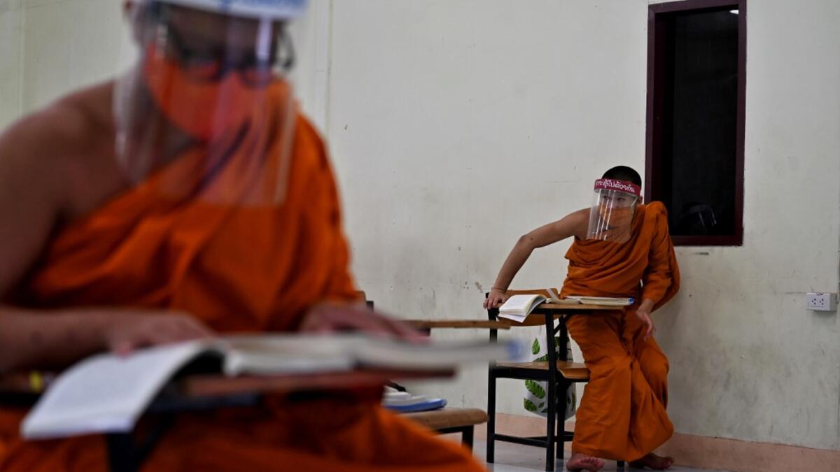 Novice monks wearing face shields as a preventive measure against the spread of the COVID-19 coronavirus attend religious studies at Wat Molilokkayaram Buddhist temple in Bangkok on April 20, 2020. Lillian SUWANRUMPHA / AFP