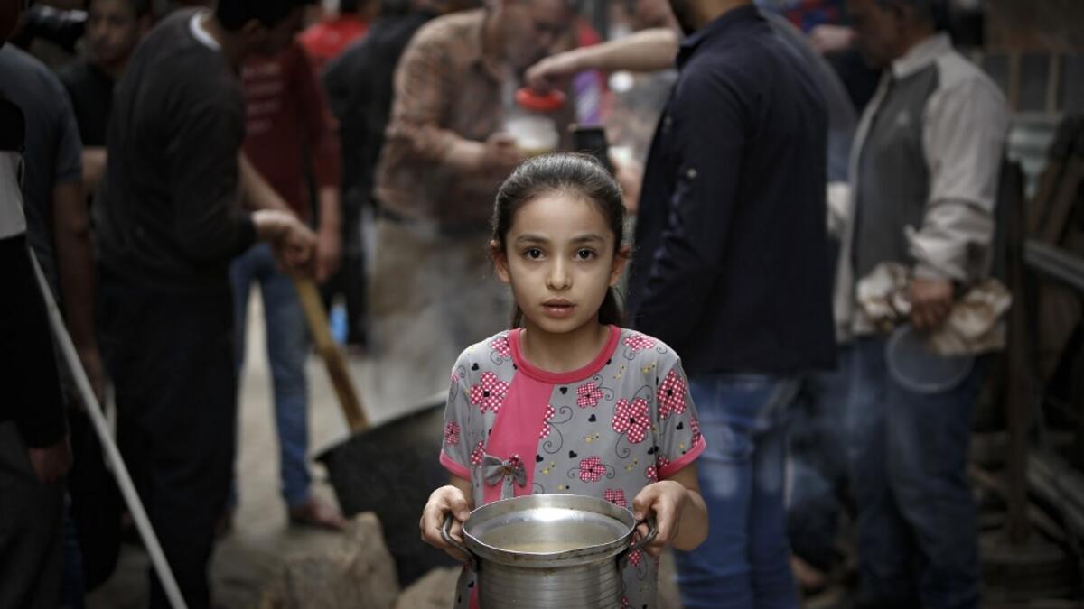 A Palestinian girl carries a portion of soup, given out to poor families, during the Islamic holy month of Ramadan in Gaza City on April 24, 2020, amid the COVID-19 coronavirus pandemic. Mohammed ABED / AFP