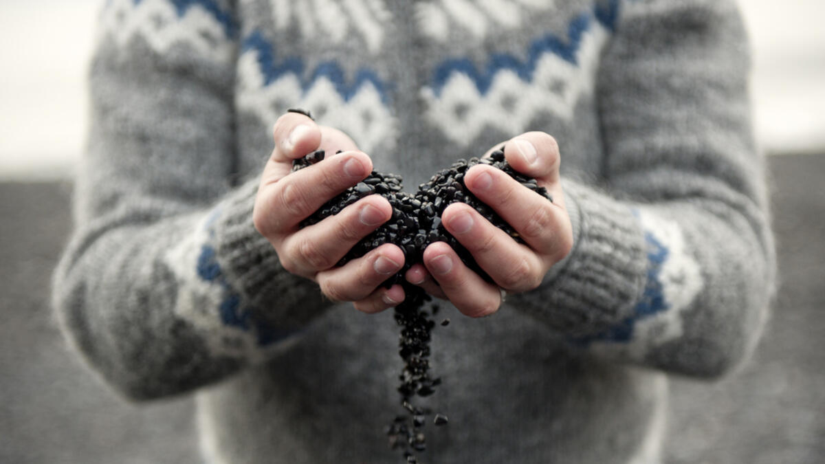 Black sand/rocks falling through fingers on a beach in Vik, Iceland (Shutterstock)