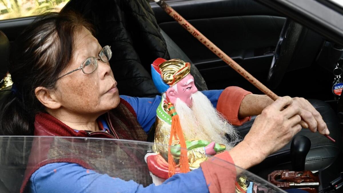 In this picture taken on March 17, 2020, a woman takes her new Taoist god statue home after it was restored by sculptor Lin Hsin-lai at his workplace in Taoyuan, northern Taiwan. Every spare surface of Lin Hsin-lai's four-storey shop is crammed with a pantheon of Taiwan's celestial beings, testament to the decades he has spent sheltering and restoring unwanted statues of gods.  Sam Yeh / AFP