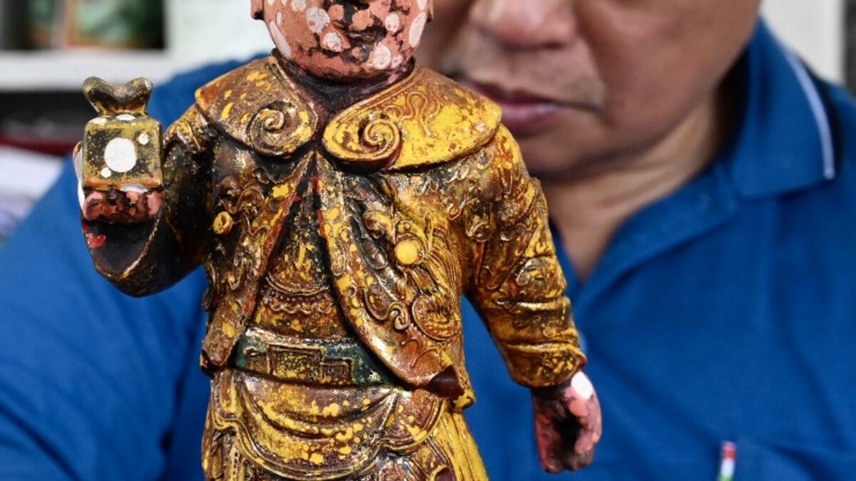 In this picture taken on March 17, 2020, sculptor Lin Hsin-lai restores a Taoist god statue at his workplace in Taoyuan, northern Taiwan on March 17, 2020. Every spare surface of Lin Hsin-lai's four-storey shop is crammed with a pantheon of Taiwan's celestial beings, testament to the decades he has spent sheltering and restoring unwanted statues of gods.  Sam Yeh / AFP