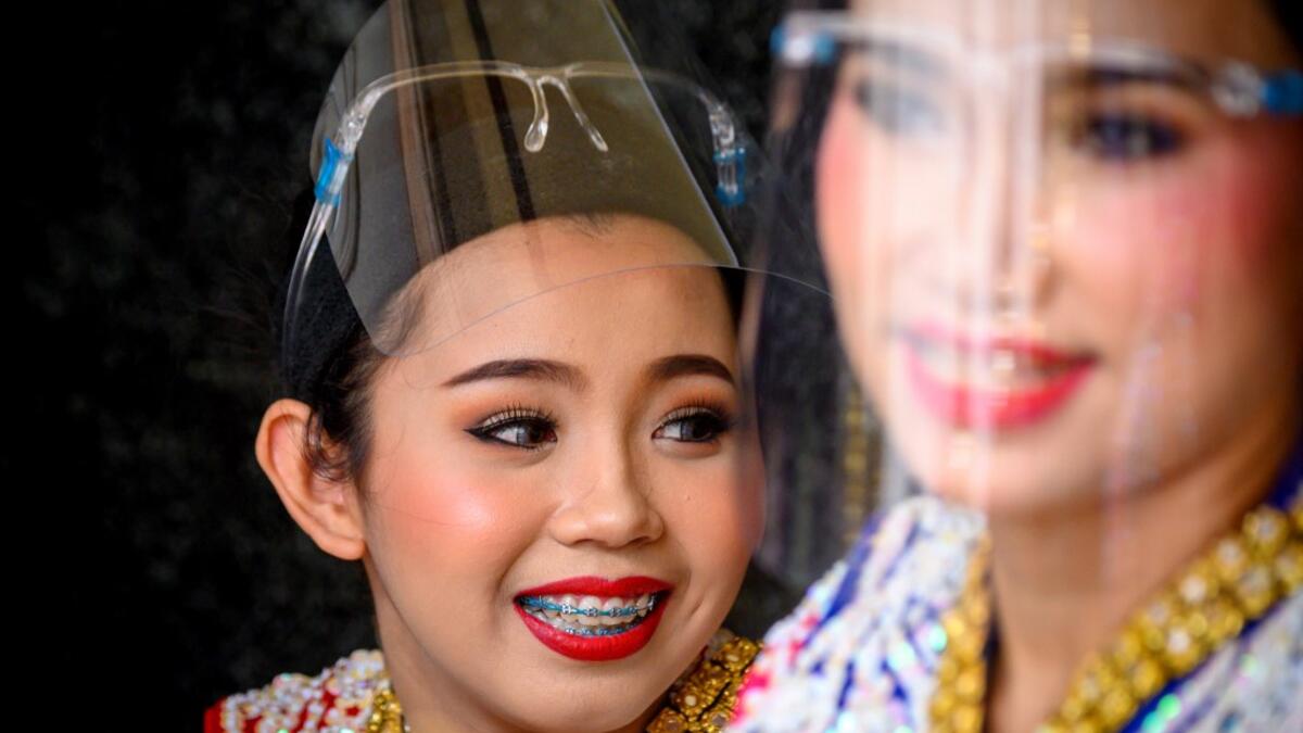 Traditional Thai dancers wearing protective face shields relax after a performance at the Erawan Shrine, which was reopened after the Thai government relaxed measures to combat the spread of the COVID-19 novel coronavirus, in Bangkok on May 4, 2020. Thailand began easing restrictions related to the COVID-19 novel coronavirus on May 3 by allowing various businesses to reopen, but warned that the stricter measures would be re-imposed should cases increase again. Mladen ANTONOV / AFP