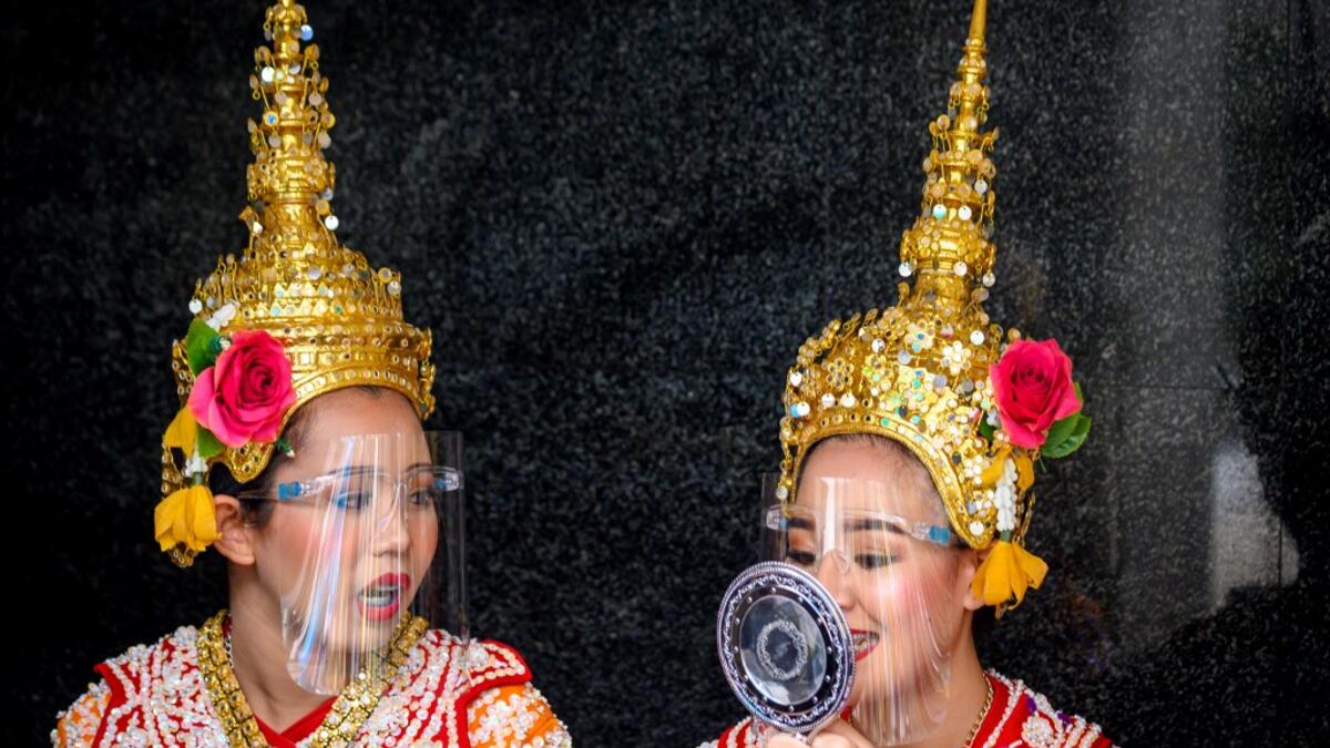 Traditional Thai dancers wearing protective face shields relax after a performance at the Erawan Shrine, which was reopened after the Thai government relaxed measures to combat the spread of the COVID-19 novel coronavirus, in Bangkok on May 4, 2020. Thailand began easing restrictions related to the COVID-19 novel coronavirus on May 3 by allowing various businesses to reopen, but warned that the stricter measures would be re-imposed should cases increase again. Mladen ANTONOV / AFP