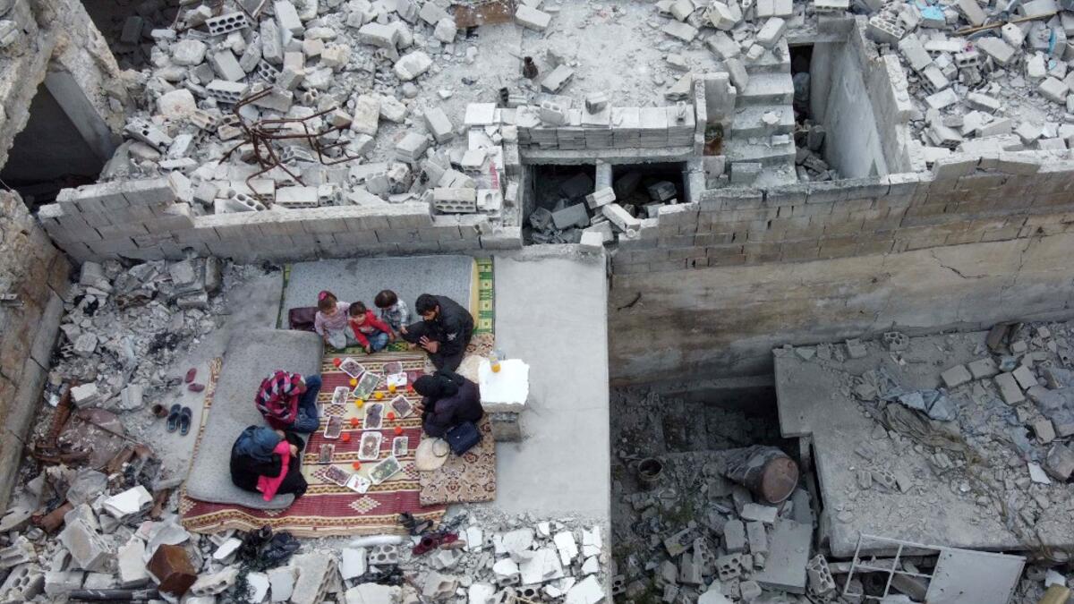 This picture taken on May 4, 2020 during the Muslim holy fasting month of Ramadan shows an aerial view of members of the displaced Syrian family of Tareq Abu Ziad, from the town of Ariha in the southern countryside of the Idlib province, breaking their fast together for the sunset "iftar" meal, in the midst of the rubble of their destroyed home upon their return to the town for one day after fleeing during the previous military assault by Syrian government forces and their allies. Aaref WATAD / AFP