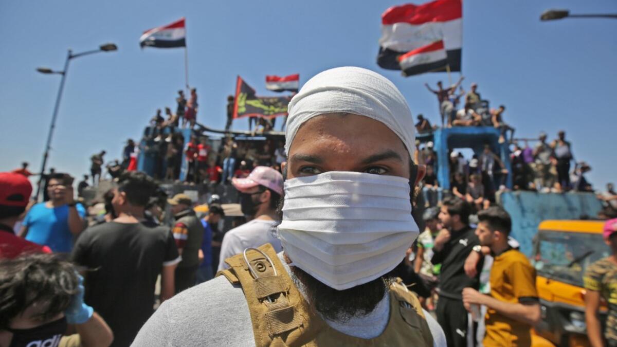 An Iraqi protester wears a face mask during an anti-government demonstration on Al-Jumhuriyah bridge in the capital Baghdad, on May 10,2020. Modest anti-government rallies resumed in some Iraqi cities today, clashing with security forces and ending months of relative calm just days after Prime Minister Mustafa Kadhemi's government came to power. AHMAD AL-RUBAYE / AFP