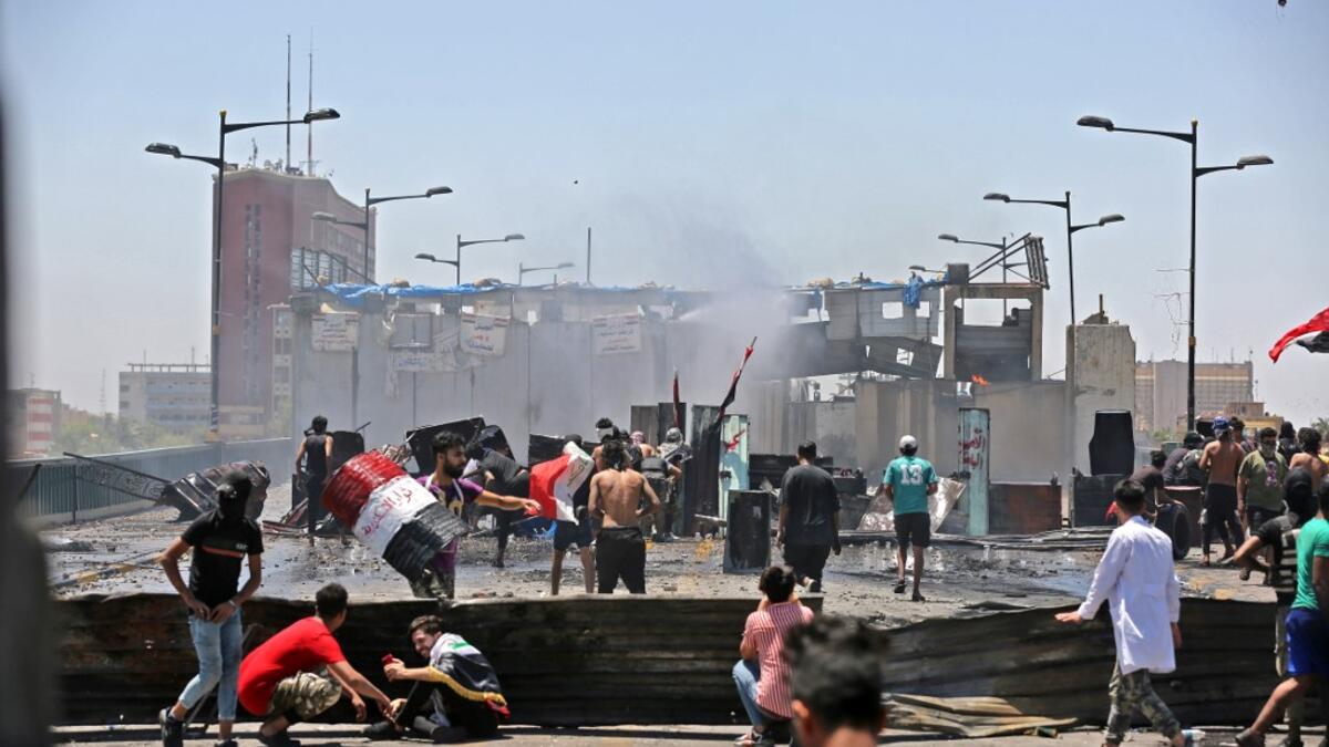 Iraqi protesters take cover as they clash with security forces during an anti-government demonstration on Al-Jumhuriyah bridge in the capital Baghdad, on May 10,2020. Modest anti-government rallies resumed in some Iraqi cities today, clashing with security forces and ending months of relative calm just days after Prime Minister Mustafa Kadhemi's government came to power. AHMAD AL-RUBAYE / AFP