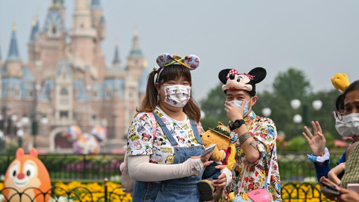 People wearing face masks visit the Disneyland amusement park in Shanghai on May 11, 2020. Disneyland Shanghai reopened on May 11 to the public after being closed since January due to the COVID-19 coronavirus outbreak. Hector RETAMAL / AFP