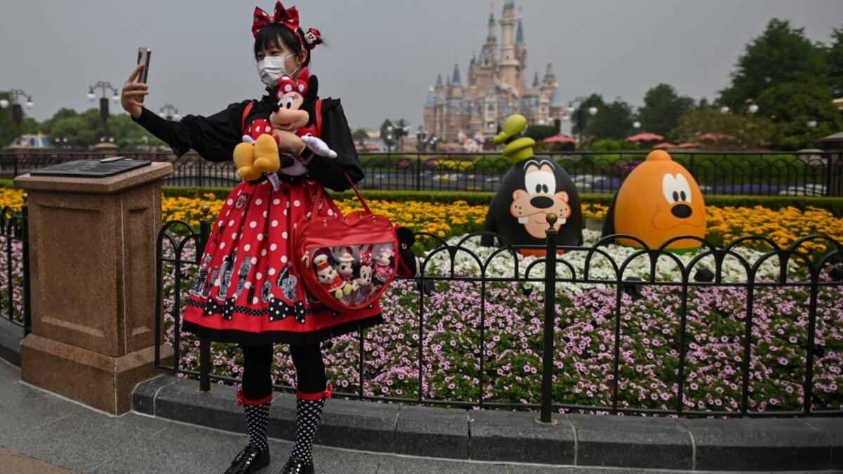 A woman wearing a face mask takes a selfie while visiting the Disneyland amusement park in Shanghai on May 11, 2020. Disneyland Shanghai reopened on May 11 to the public after being closed since January due to the COVID-19 coronavirus outbreak. Hector RETAMAL / AFP